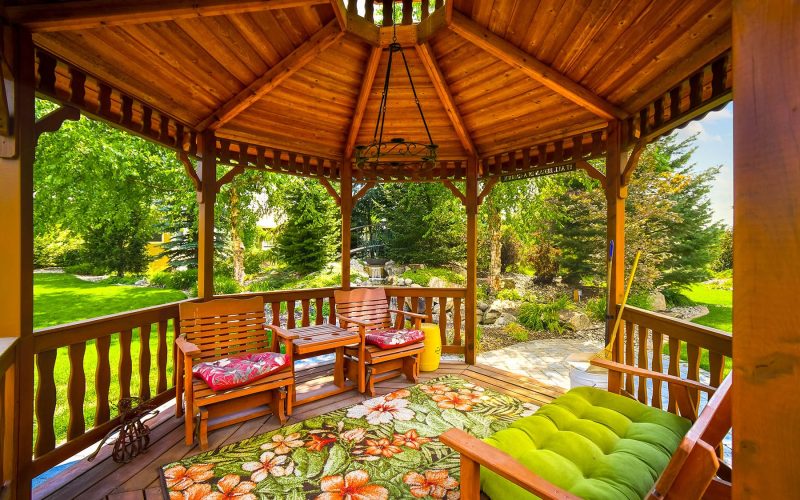 View from inside a cedar wooden gazebo in the back yard garden of a well landscaped home.