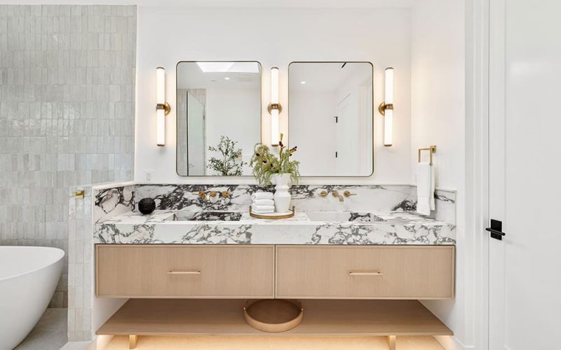 Modern bathroom with marble countertop, dual mirrors, and elegant lighting, featuring a stylish vanity and decorative accents.